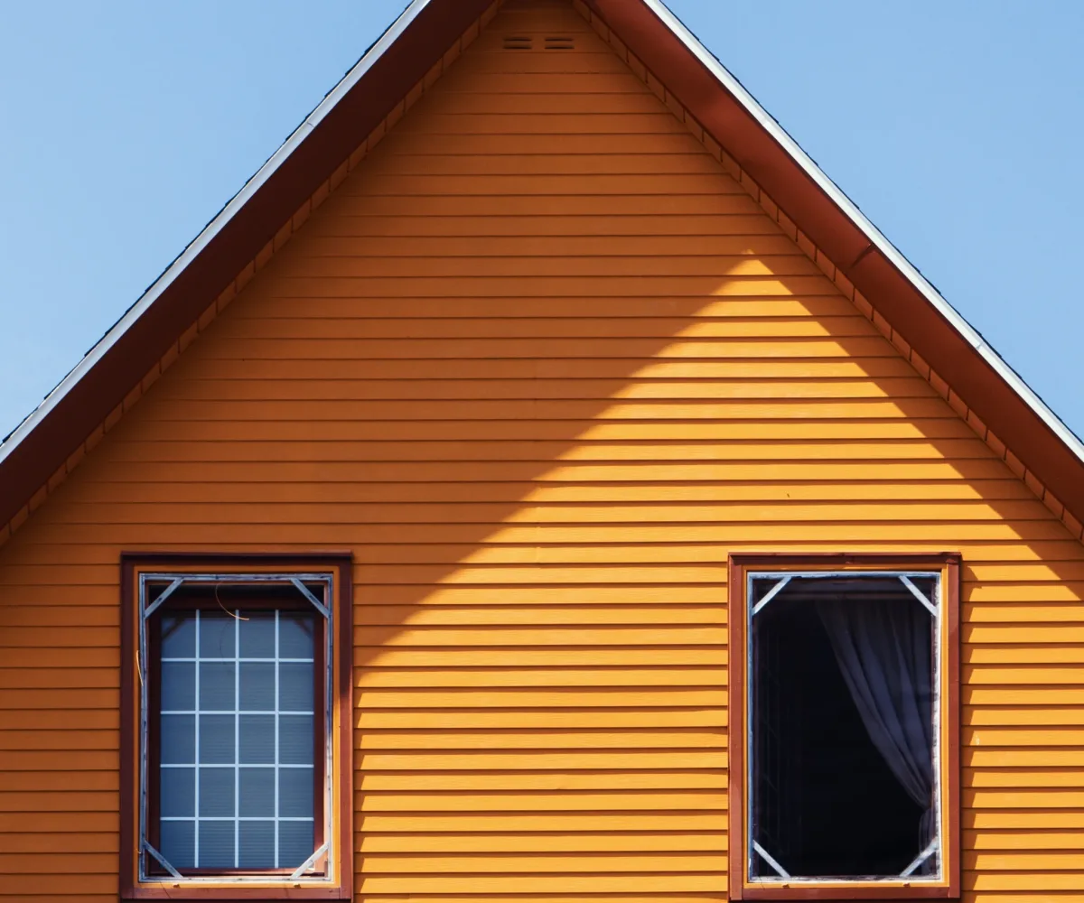A vertical shot of a wooden orange house under the clear blue sky